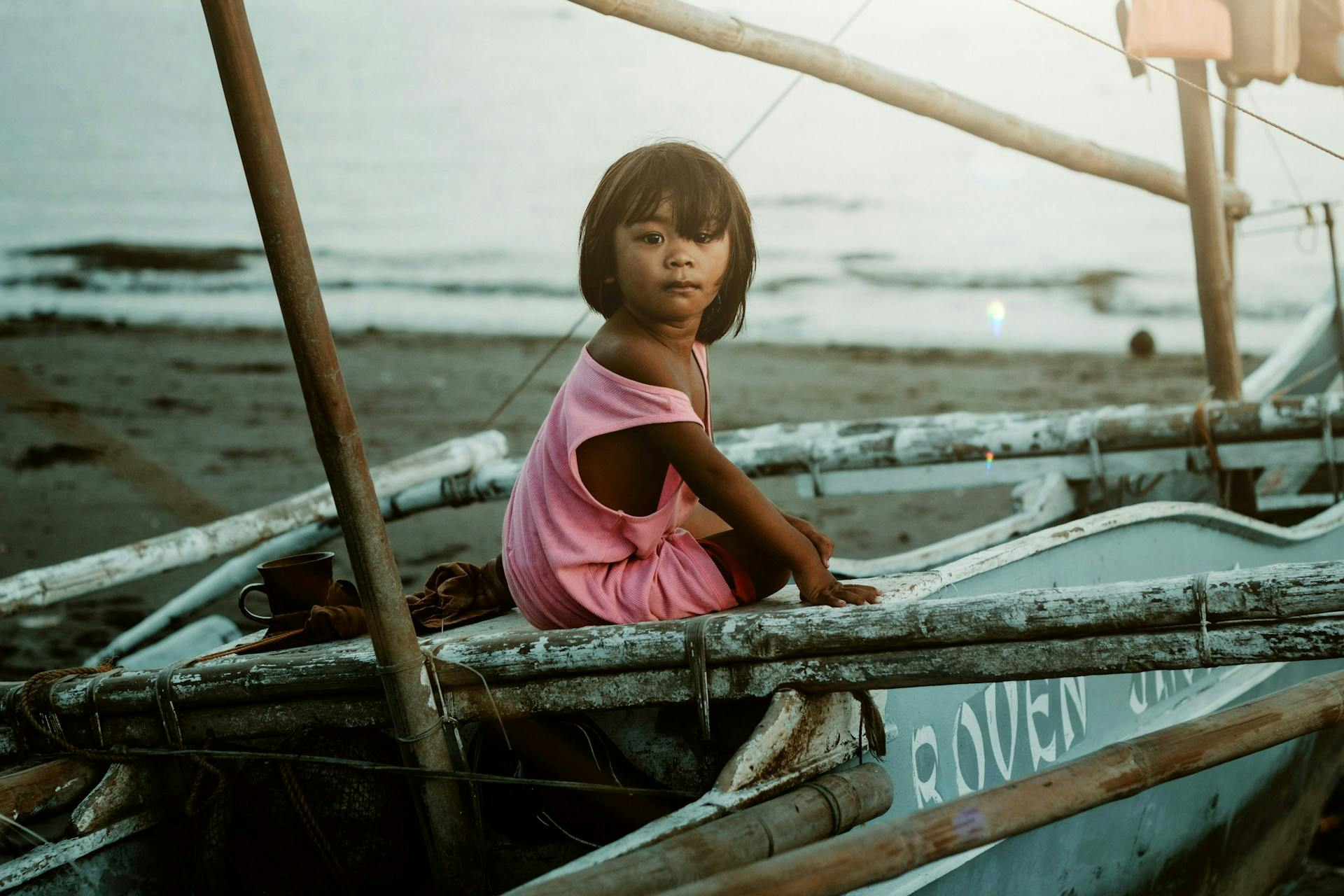 Girl sat on a boat on a beach in Iloilo